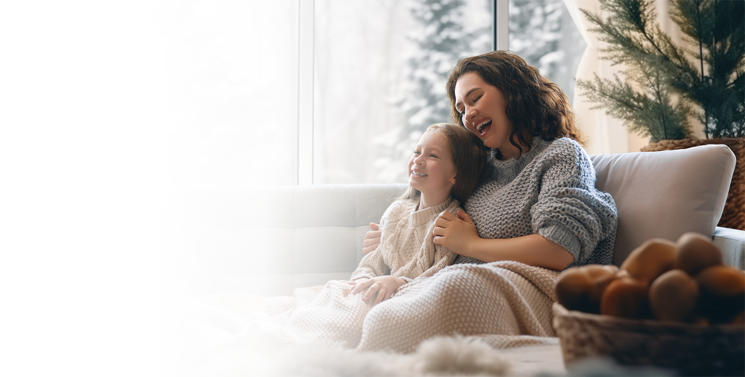 Woman and child sitting on a couch under a blanket