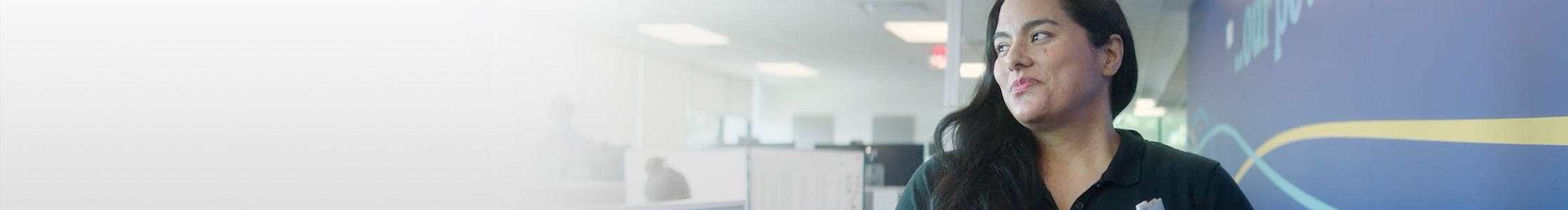 Woman wearing a dark blue polo shirt in a corporate office