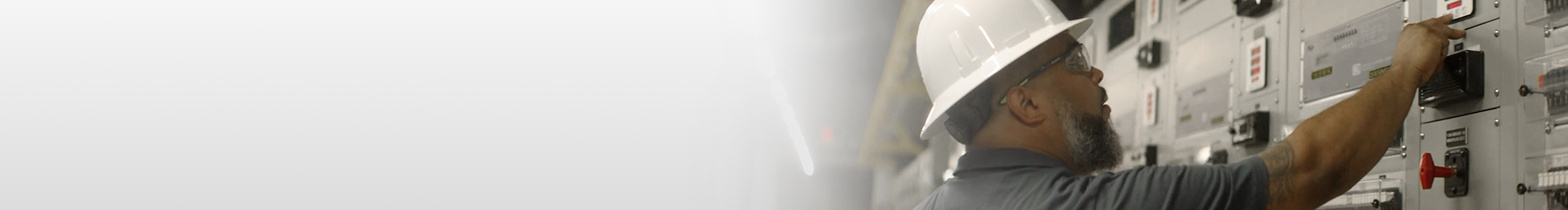 Man in a white hard hat checking electrical equipment
